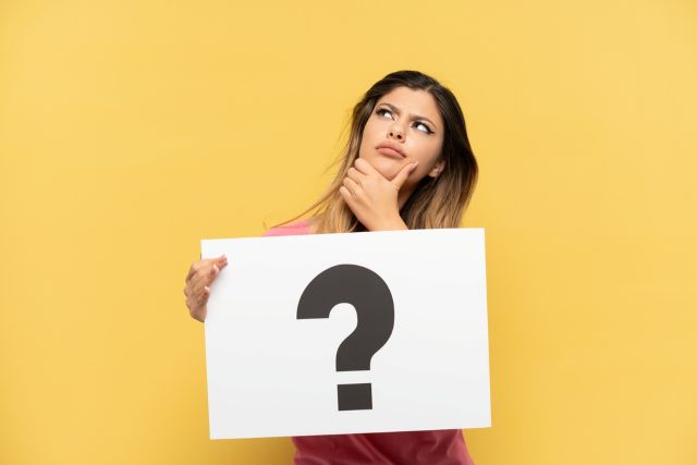 ハテナマークを持つ女性