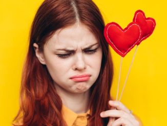 赤いハートを持ちながら悲しい顔をする女性